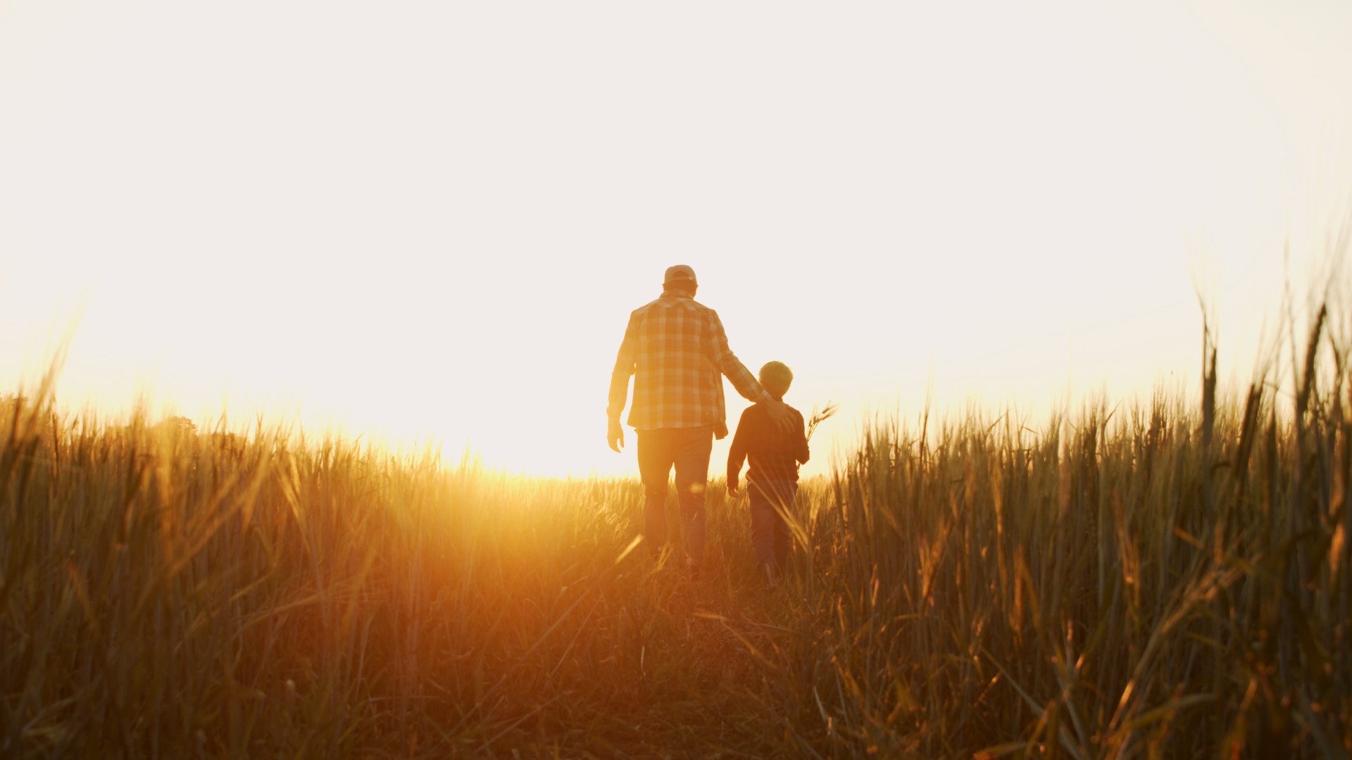 father and son walking into sunset